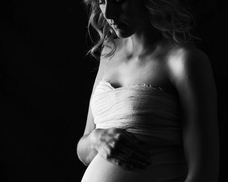 Pregnant woman in side light against black background