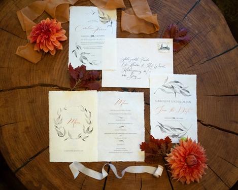 Wedding stationery on rustic brown wooden table with orange dahlias