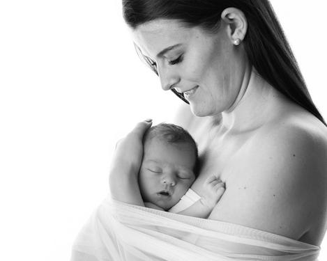 Mutter mit ihrem schlafenden Baby umhüllt von einem weißen Tuch