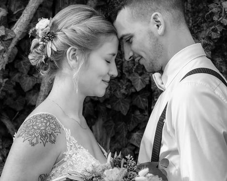 Bridal couple standing forehead to forehead, in front of them the bridal bouquet, b/w picture