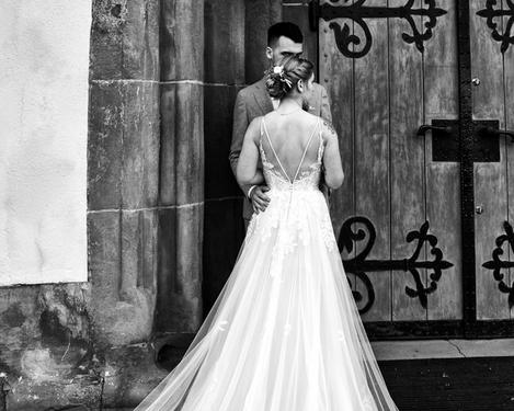 Rückenansicht der Braut mit Bräutigam vor einem alten Eingangsportal, s/w Bild
