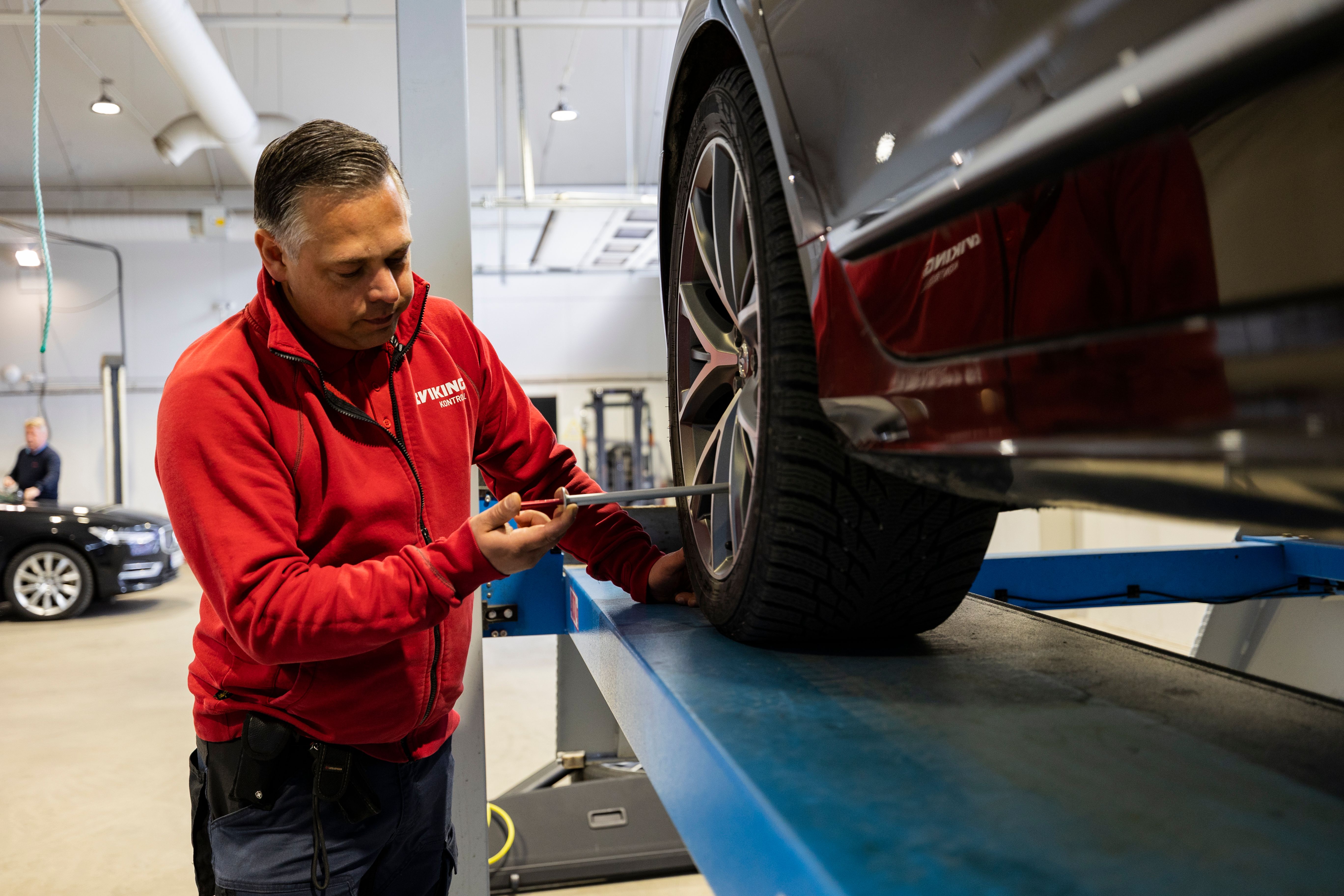 Man utför kontroll på bil.