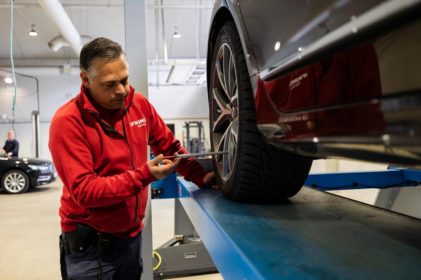 Man utför kontroll på bil.
