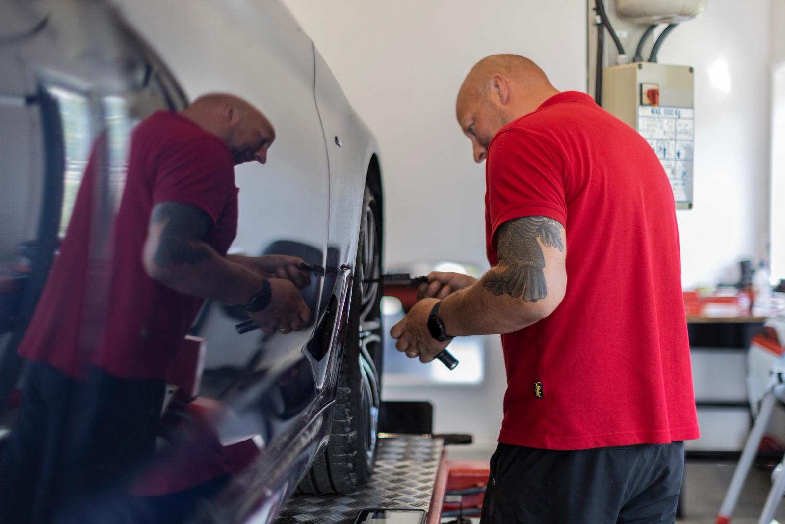 Man kontrollerar hjulen på en bil.