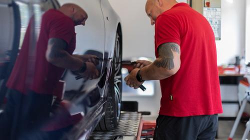 Man kontrollerar hjulen på en bil.