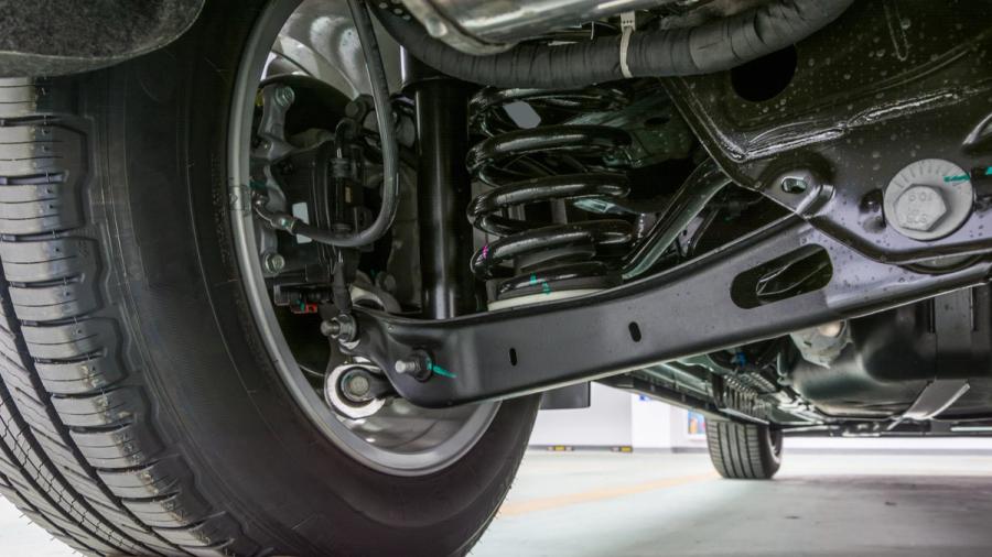 Lähikuva auton takajousitusjärjestelmästä, mukaan lukien jousi, ohjausvarsi ja rengas.