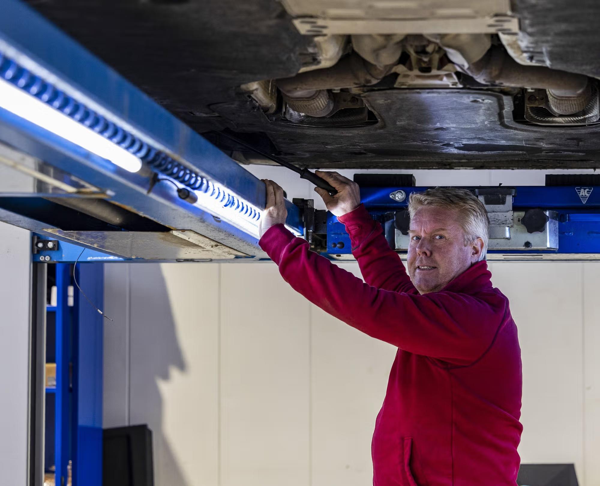 Man kontrollerar underdelen av en bil