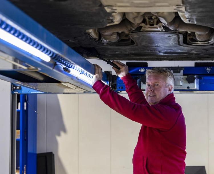 Man kontrollerar underdelen av en bil