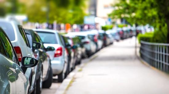 Biler parkert langs veien i henhold til parkeringsregler og parkeringsskilt.