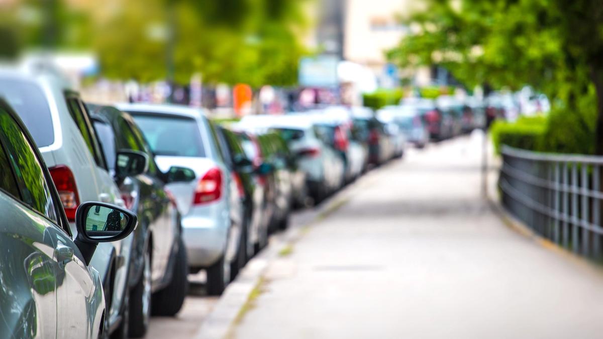 Biler parkert langs veien i henhold til parkeringsregler og parkeringsskilt.