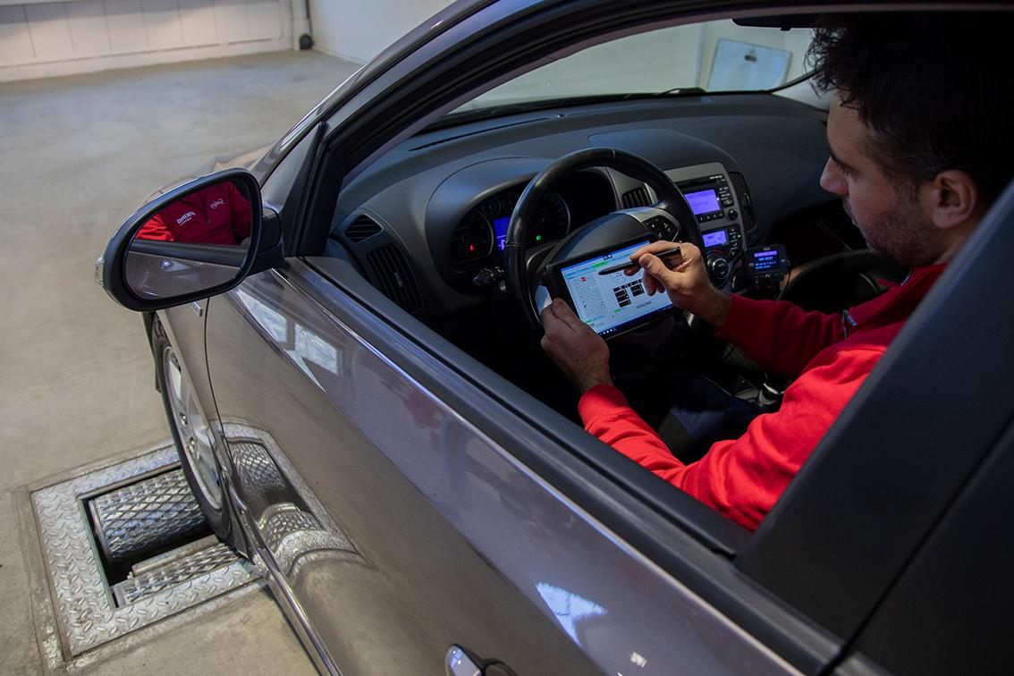 Mann utfører kontroll fra førersetet i bil.