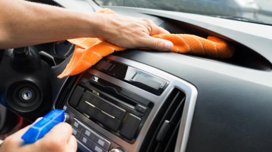 En hand vaskar dashboardet på innsidan av en bil.