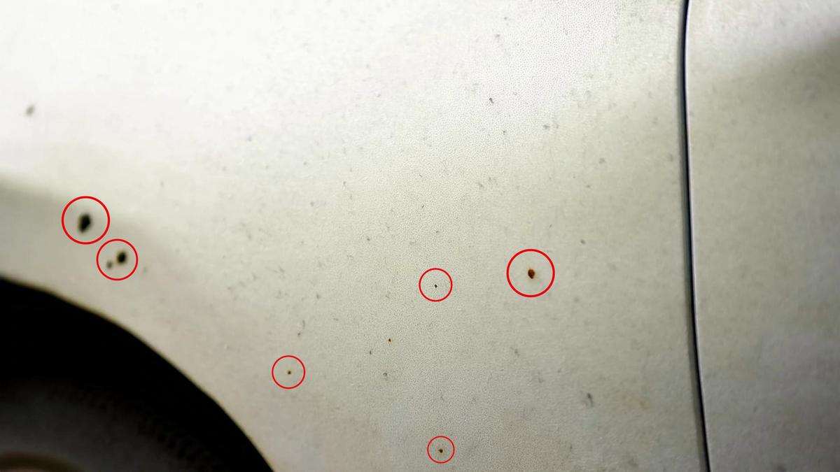 Nærbilde av en hvit bil med mange små rustflekker ofte kalt flyverust.