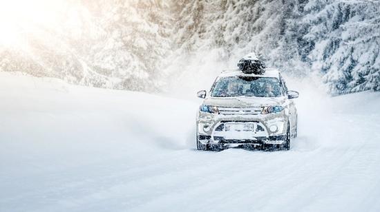 Bil som kjører i snøvær på en snødekket vei om vinteren.