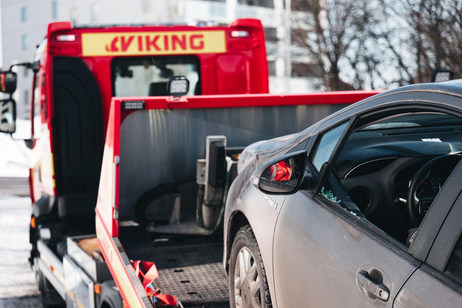 Viking hinausauto lastaamassa harmaata autoa, jonka kuljettajan sivuikkuna on rikki.