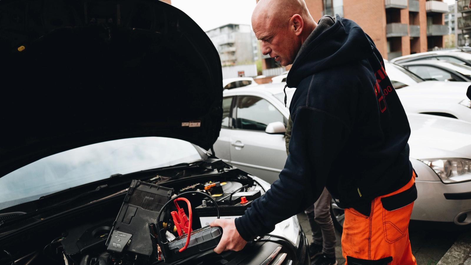 Henkilö käynnistää autoa apukäynnistimellä.