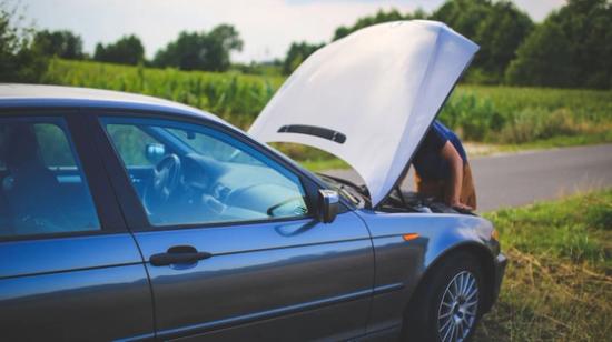 Person tittar under huven på en bil.