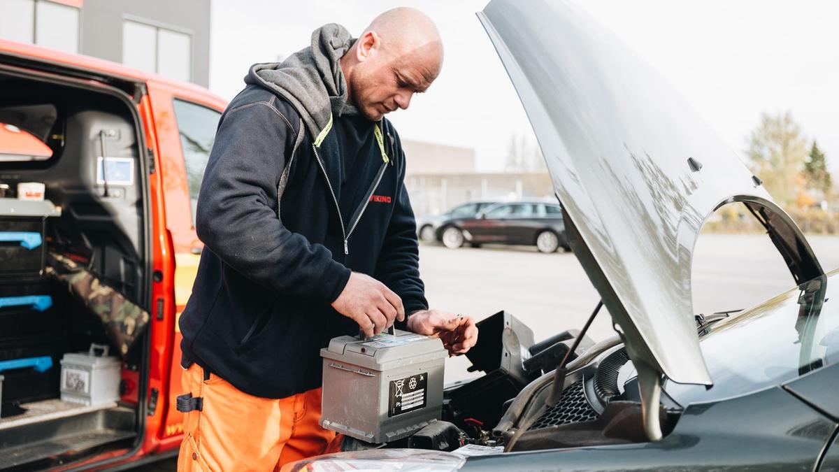 Man byter batteri på bil.