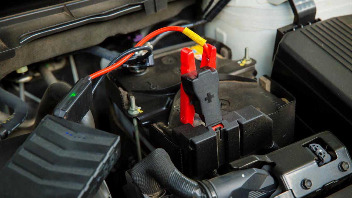 A car battery with an auxiliary starter attached with a red and black starter cable.