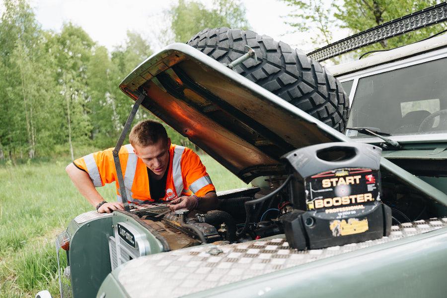 Man startar ett bilbatteri med hjälp av en booster.