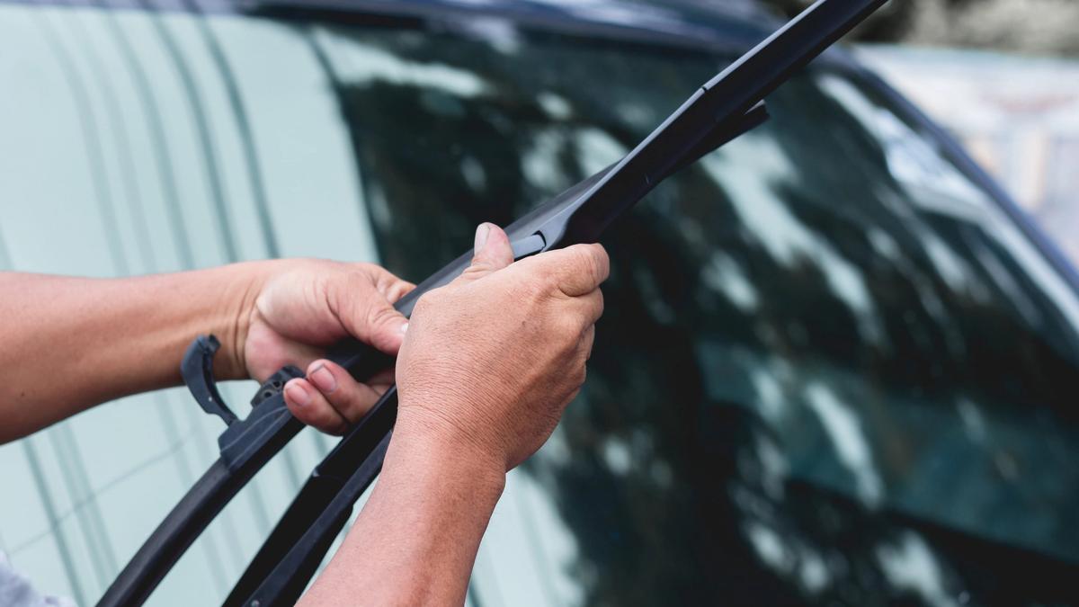 Person som skifter vindusviskere på bilen sin.