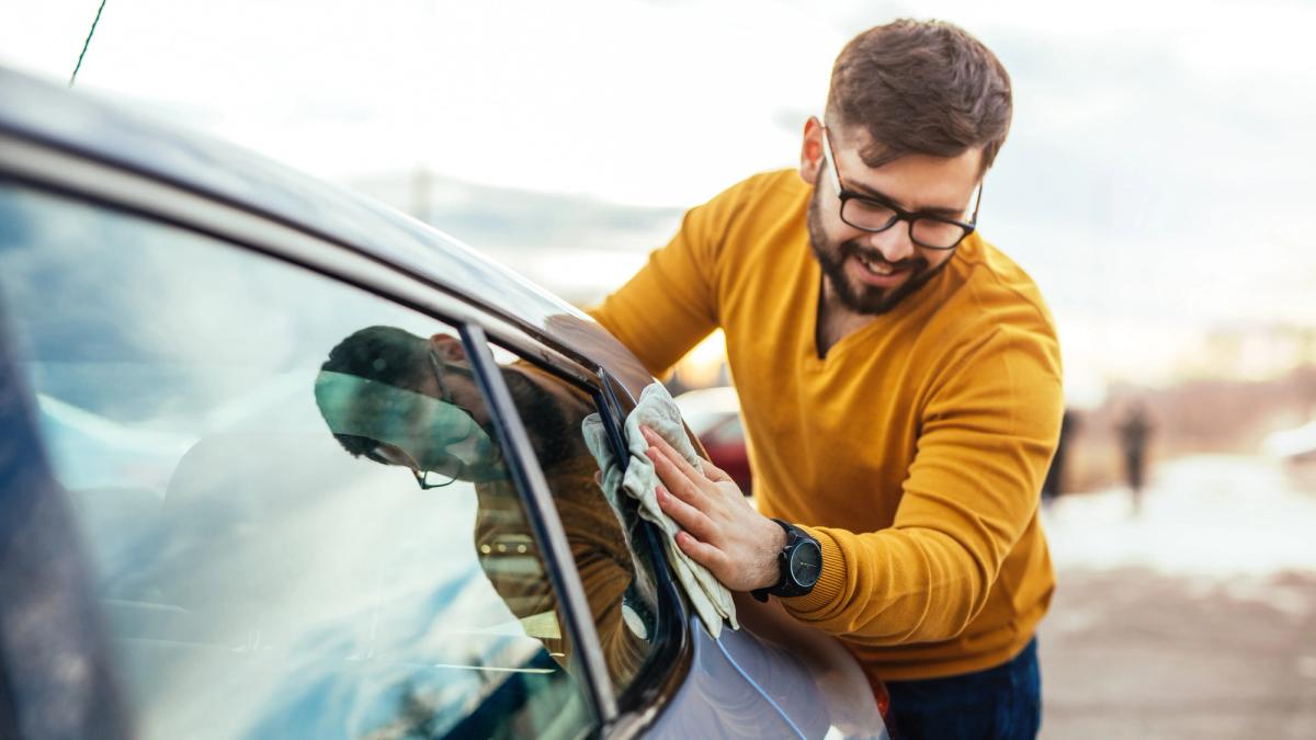 Person som polerer bilen sin på høsten.