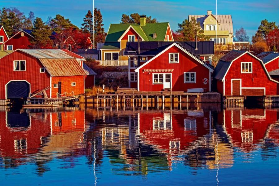 Röda hus med vita knutar längst vattnet vid Höga kusten.