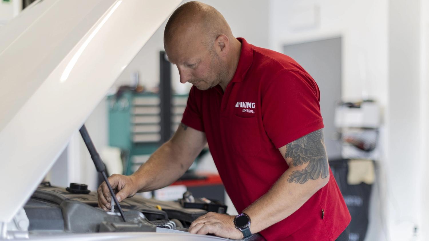 Takstmann som sjekker motorrommet på en bruktbil.