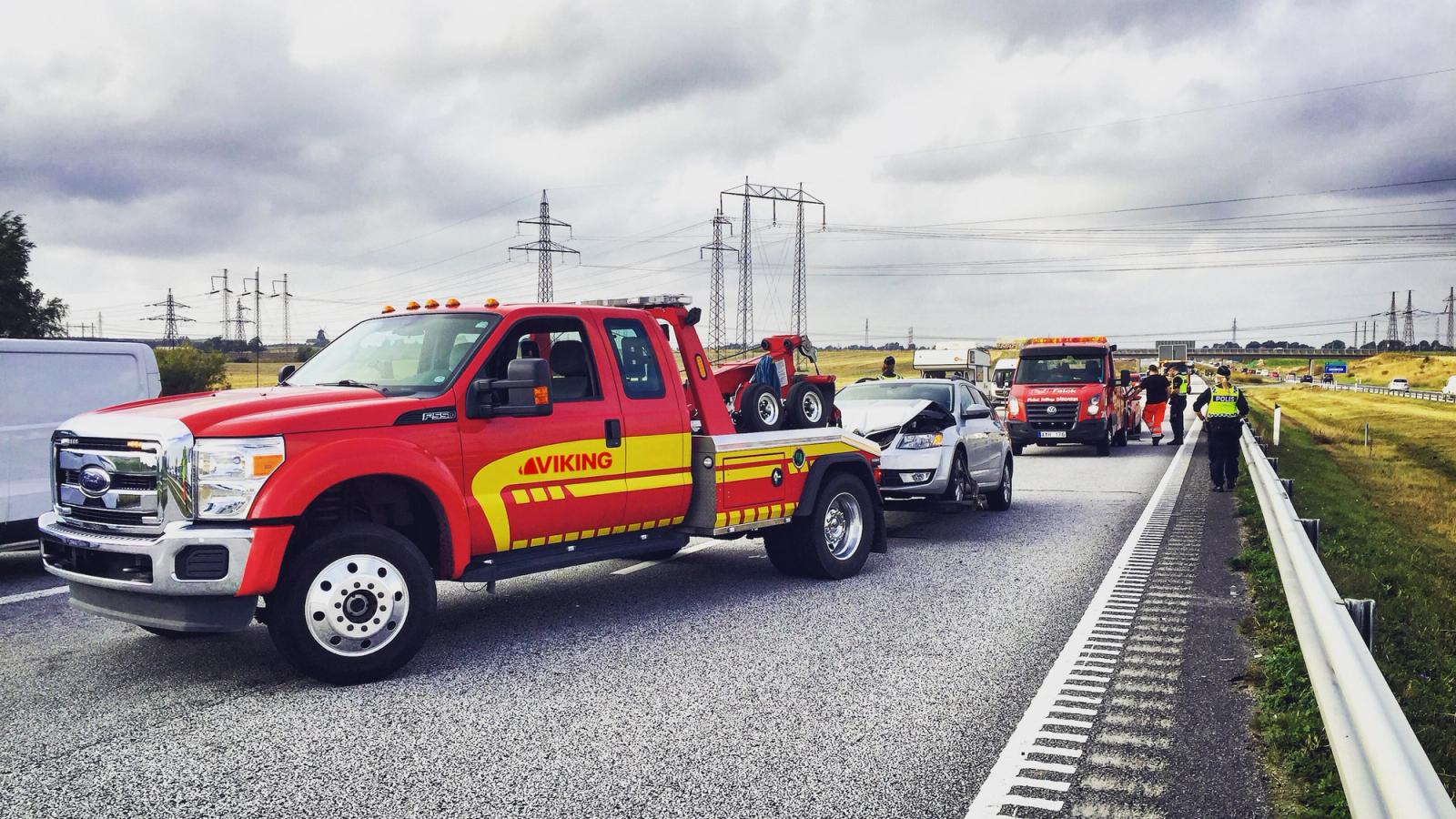 Punainen Viking-hinausauto ja hätäajoneuvot ovat valtatiellä avustamassa auto-onnettomuuspaikalla.