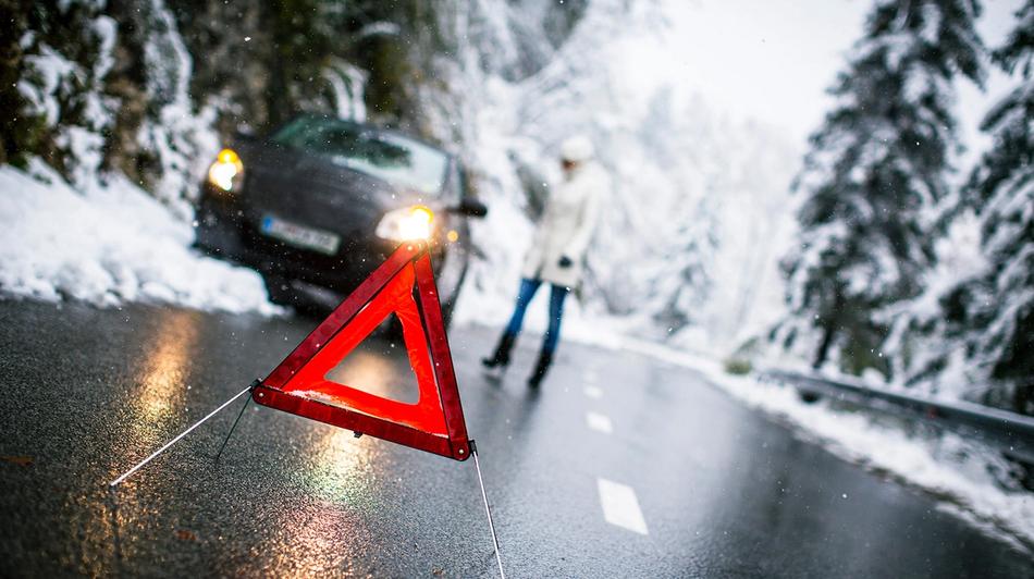Auto pysäköity tien reunaan, varoituskolmio etualalla.