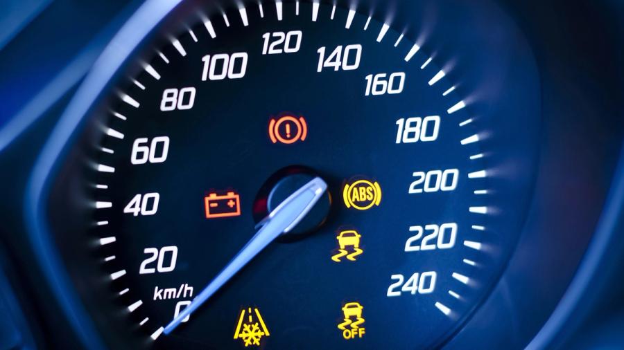 Nærbilde av et bilspeedometer som viser forskjellige varsellys, inkludert bremse, batteri, ABS og traction control.