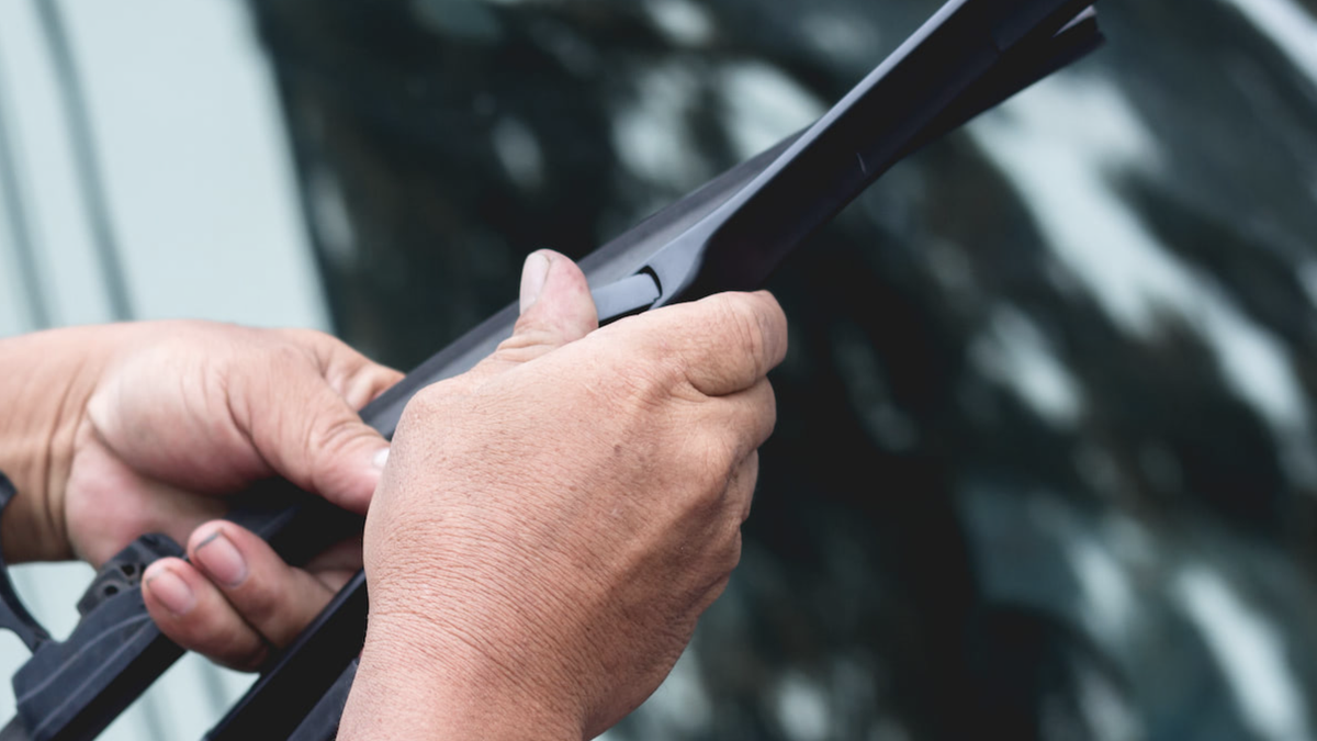 Person byter vindrutetorkare.