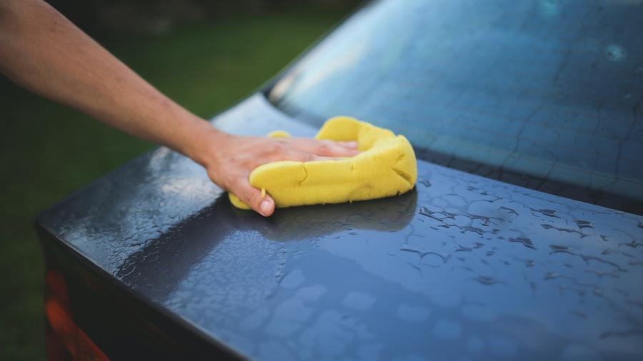 Person som håndvasker bilen utvendig.