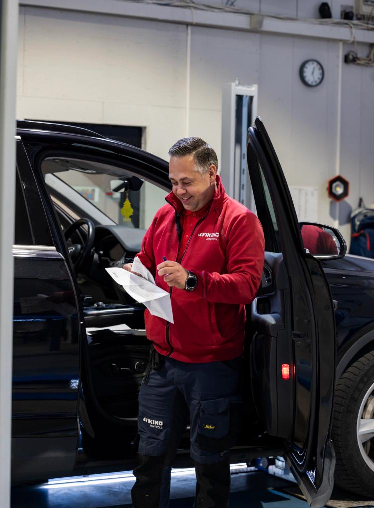 Mann utfører kontroll av bil.