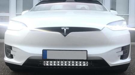 Etunäkymä valkoisesta Teslasta, jonka eturekisterikilven alle on asennettu LED-valopalkki.