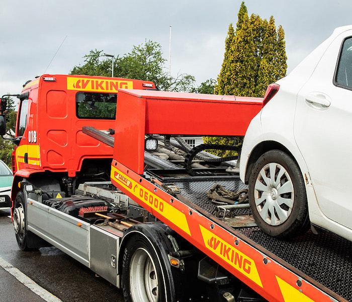 A Viking tow truck is towing a white car.