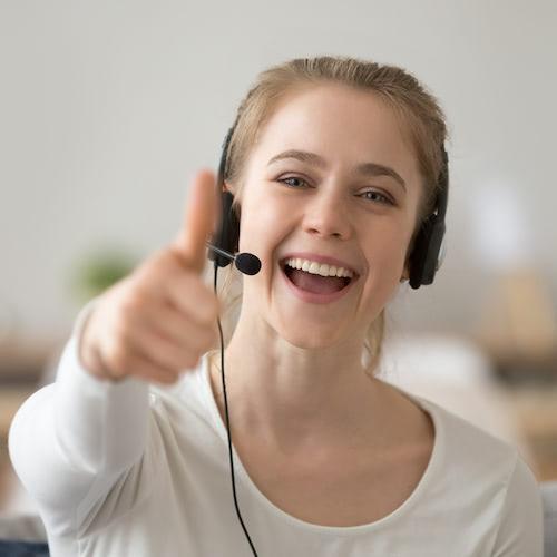 Smilende kundeservicemedarbejder giver tommelfingeren op.