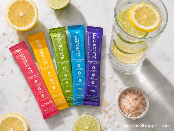 Electrolyte powder packets and glass of citrus water flat lay on white marble