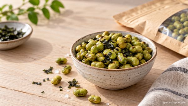 Bowl of roasted edamame beside seaweed seasoning and individual snack packs.