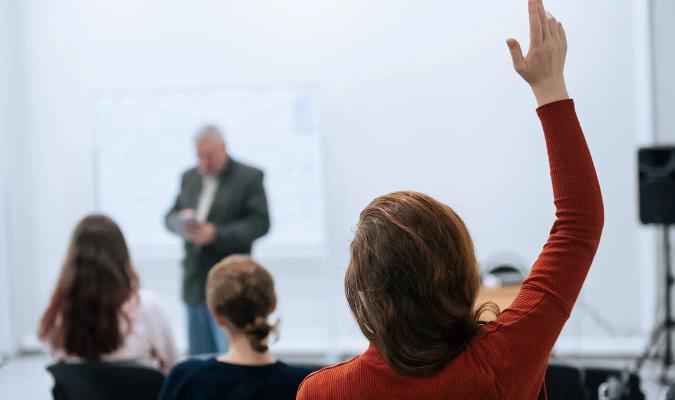 Kvinne rekker opp hånden i møte