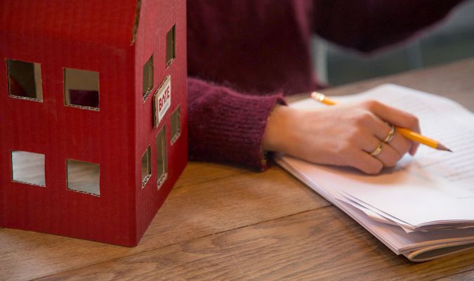 Hånd holder blyant over skriveblokk