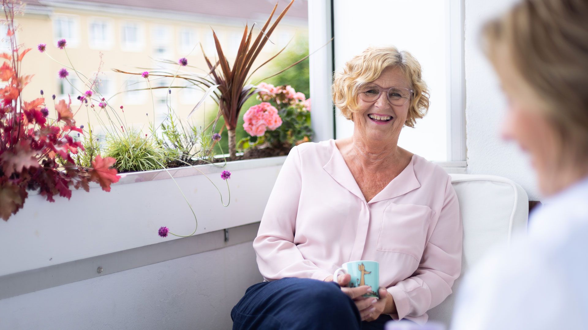 Dame drikker kaffe på balkongen sin