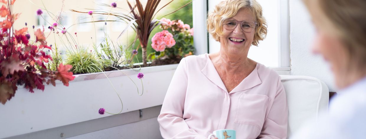 Dame drikker kaffe på balkongen sin