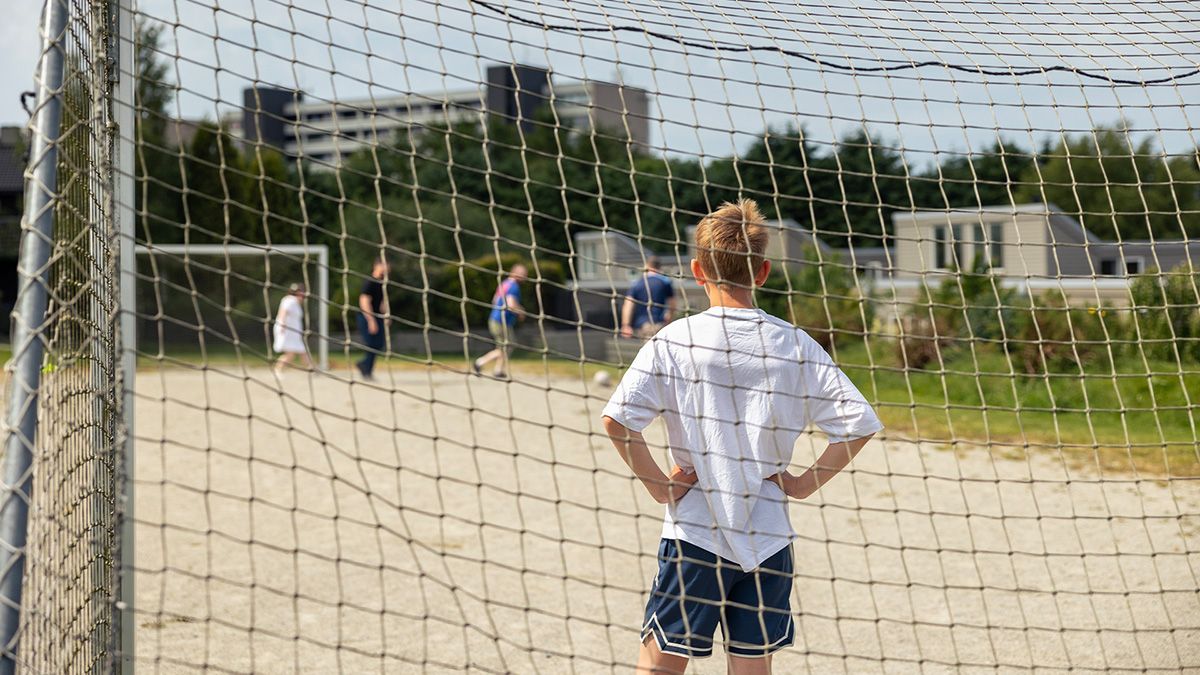 gutt med ryggen til i mål på fotballkamp på grusen