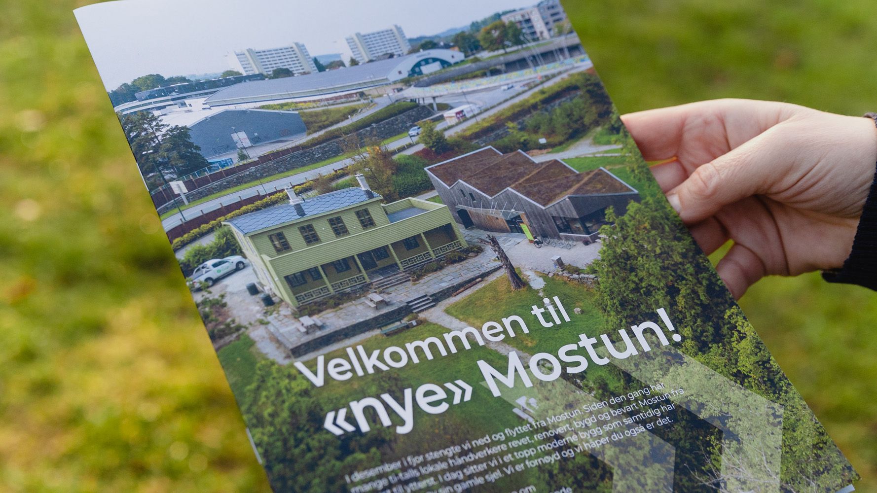 hånd som holder et blad med bilde av et grønt hus