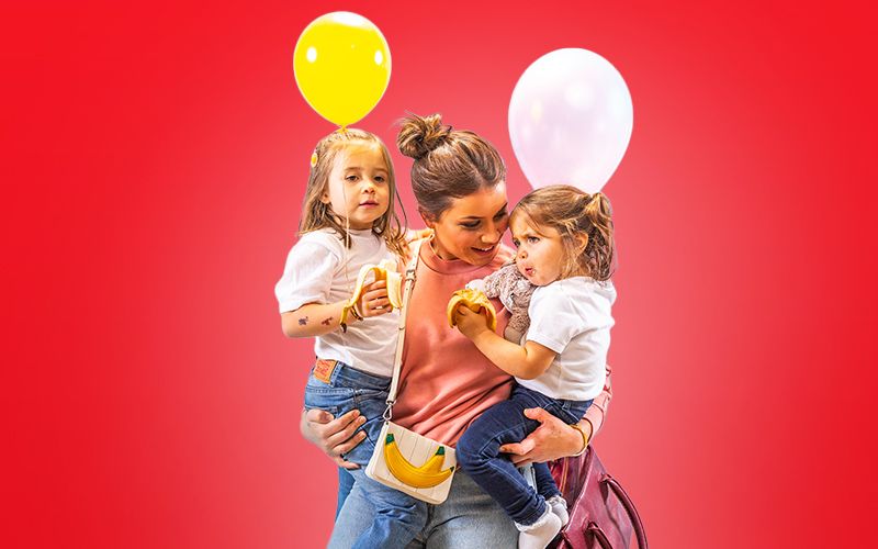 dame med to barn som holder ballonger