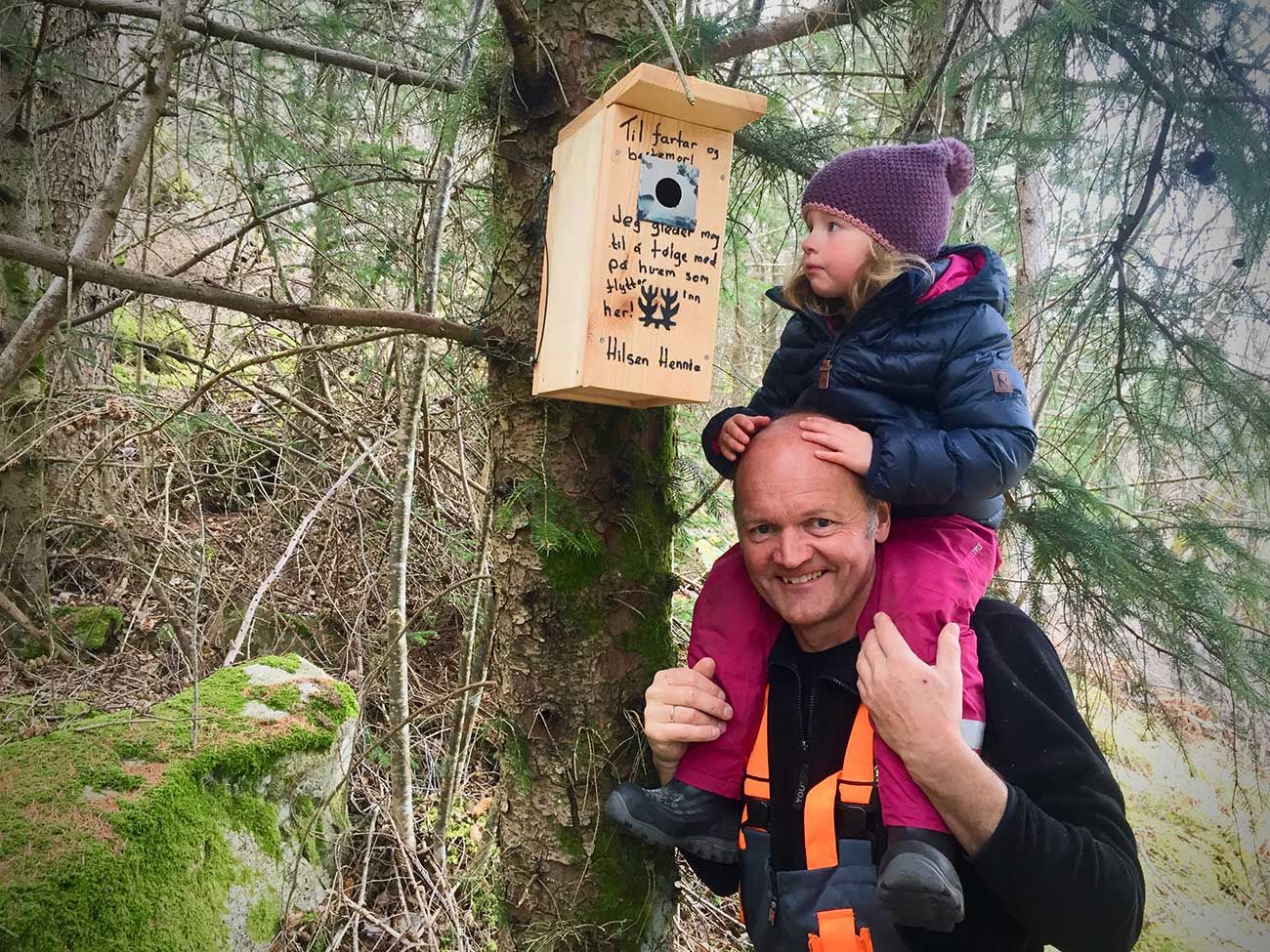 far og datter ved siden av en fuglekasse