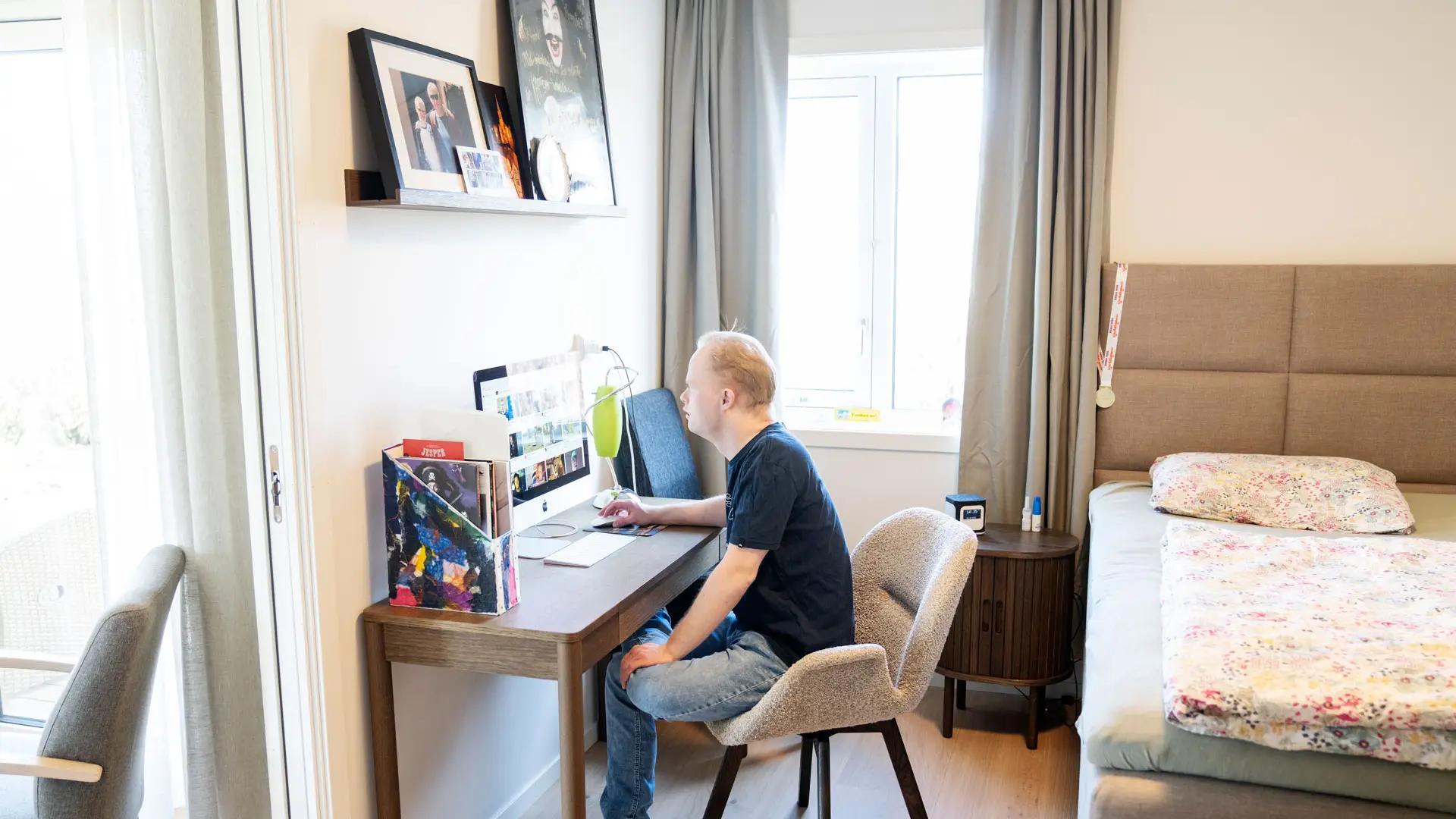 mann sitter ved skrivepult og ser på pc-skjerm