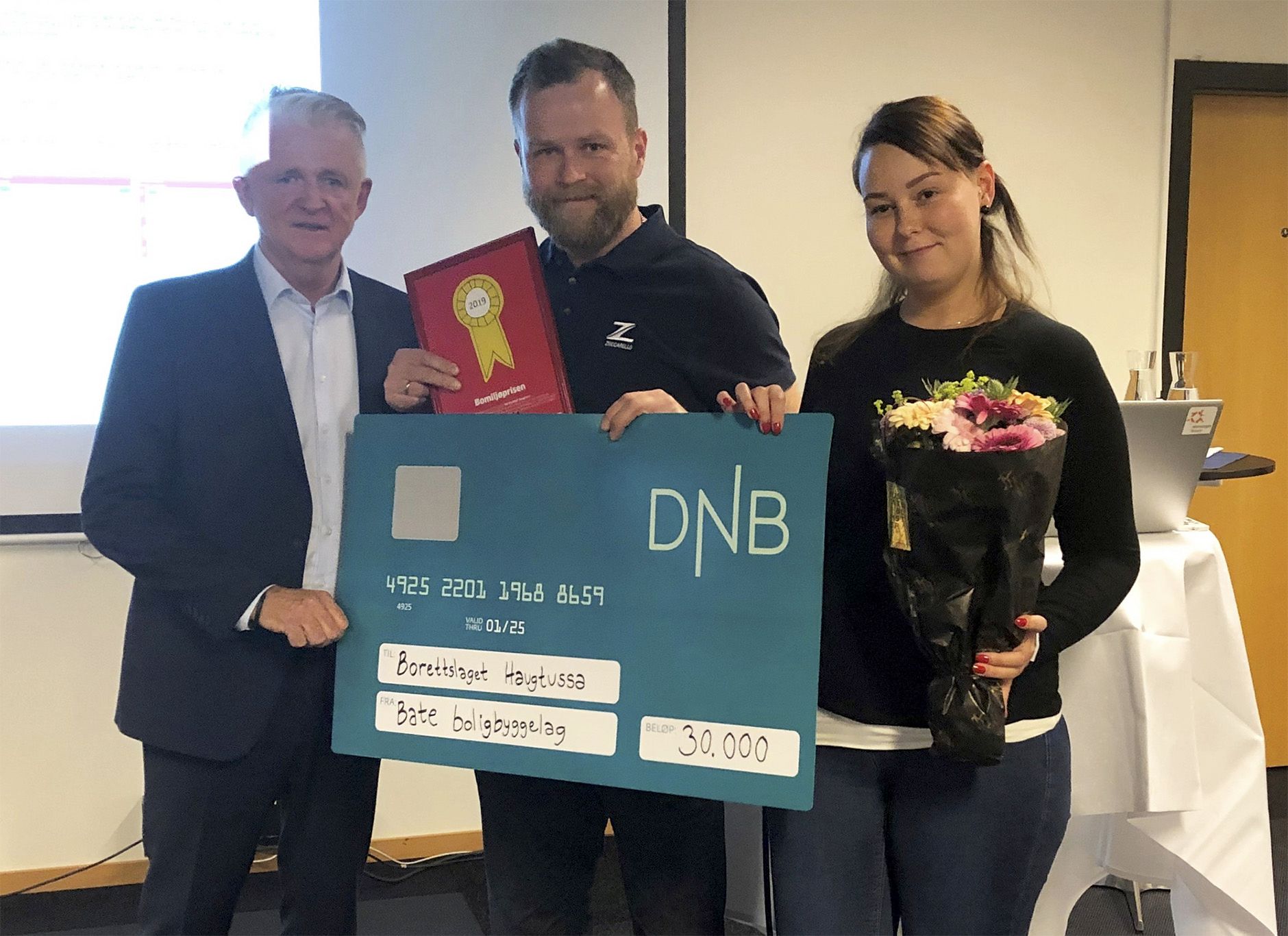 Tre personer med en gavesjekk fra dnb