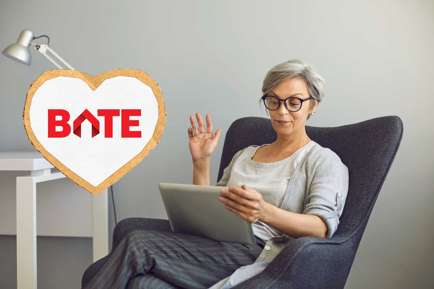 Dame som sitter i en stol og rekker hånden i været, deltar på digitalt møte